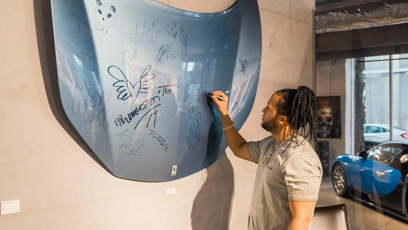 el alfa signing the ferrari hood from mph club exotic car rental